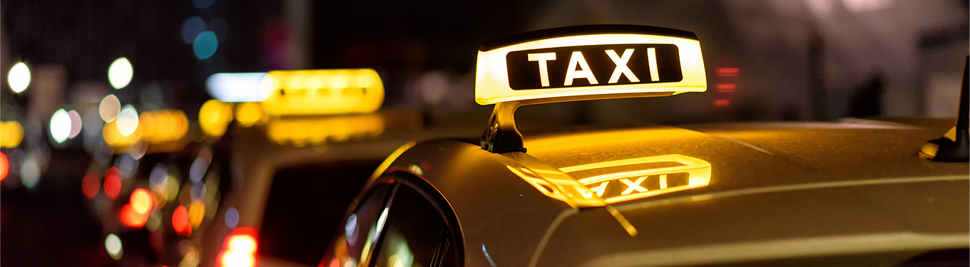 A line of taxis with their rooflights lit